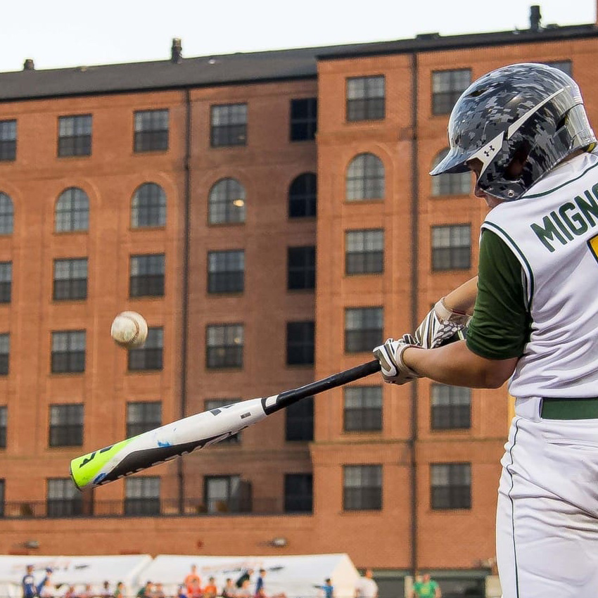 A young baseball batter connects with a pitch